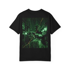 May include: A black short-sleeve t-shirt featuring a large graphic print on the back. The design depicts a traditional Japanese street scene with a pagoda, rendered in a digital green matrix code style with a diagonal orange lightning bolt streak.