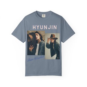 May include: A slate blue short-sleeve t-shirt featuring the text HYUNJIN in light pink at the top and Bias Wrecker in blue script at the bottom. The center displays two rectangular photographic prints of a person wearing a brown fedora hat.