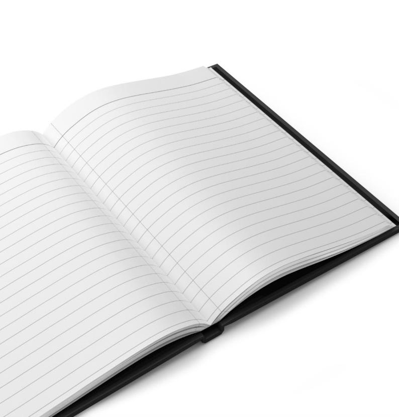 May include: An open notebook with a black cover and white pages featuring thin horizontal black lines. The notebook is positioned at an angle, displaying the interior paper layout with a clear view of the lined pages and the dark binding spine.