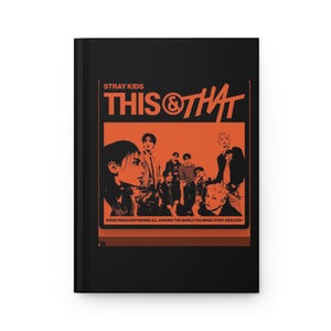 May include: A black hardcover notebook featuring an orange graphic print on the front cover. The design includes the text STRAY KIDS THIS & THAT and a group of people, with the text STRAY KIDS EVERYWHERE ALL AROUND THE WORLD YOU MAKE STRAY KIDS STAY.
