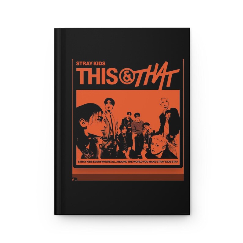 May include: A black hardcover notebook featuring an orange graphic print on the front cover. The design includes the text STRAY KIDS THIS & THAT and a group of people, with the text STRAY KIDS EVERYWHERE ALL AROUND THE WORLD YOU MAKE STRAY KIDS STAY.