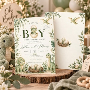 May include: A baby shower invitation card featuring green watercolour dinosaur illustrations, a nest with eggs, and botanical foliage. The text reads A LITTLE BOY IS HATCHING SOON, Lillian and Marcus, Friday April 21, 2:00 PM - 5:00 PM, Celebration Hall, 789 Street Drive, Any City, ST 01234.