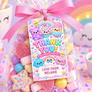 Peut inclure: Un sachet en cellophane irisé transparent rempli de bonbons assortis, incluant des biscuits en forme d'étoile et des guimauves. Une étiquette rectangulaire est attachée avec un ruban rose, portant le texte THANK YOU for celebrating with me! LOVE FROM MELANIE.