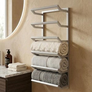 May include: A wall-mounted silver metal towel rack featuring five horizontal storage tiers. Three of the tiers hold rolled towels in varying shades of cream, light grey, and dark grey, while the top two tiers remain empty for additional storage.