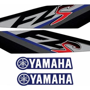 Puede incluir: Dos calcomanías alargadas y angulares con el texto FZ-S en negro y rojo, acentuadas con formas geométricas azules y grises. Debajo hay dos calcomanías rectangulares azules con el logotipo y el texto de Yamaha en color blanco.