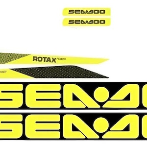 May include: A set of adhesive decals featuring two large black and yellow SEA-DOO logos, two smaller yellow SEA-DOO logos, and two elongated yellow and black patterned strips with the text ROTAX POWER printed in black on each piece.