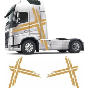 May include: A silver semi-truck cab featuring a large, gold-colored cross decal with a distressed, brush-stroke texture on the side. Below the truck, two separate gold cross decals with the same distressed design are displayed on a white background.