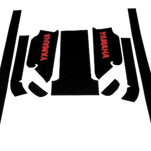 May include: A set of black adhesive traction mats for a vehicle, featuring two pieces with the red text YAMAHA printed on them. The collection includes a large central panel, two side panels, two long vertical strips, and two small curved pieces.