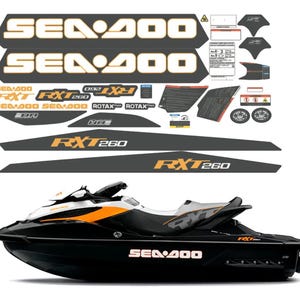Puede incluir: Una moto acuática negra, blanca y naranja con un conjunto de calcomanías a juego. Las pegatinas incluyen el texto SEA-DOO, RXT 260 y ROTAX, junto con varias etiquetas de advertencia de seguridad y formas geométricas para el vehículo.