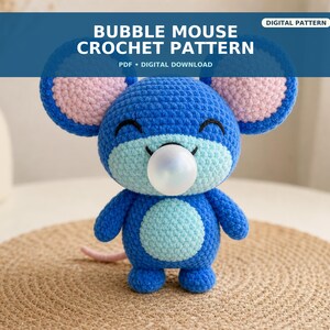 May include: A blue crocheted mouse toy with large round ears featuring pink centers, a light blue belly and face patch, and a white bubble gum sphere in its mouth. The text BUBBLE MOUSE CROCHET PATTERN PDF DIGITAL DOWNLOAD is displayed above the toy.