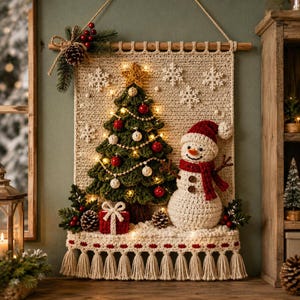 May include: A cream-colored crocheted wall hanging featuring a green Christmas tree with red and white ornaments, a snowman with a red hat and scarf, a red gift box, and white snowflakes. The piece is illuminated by small lights and has tassels.