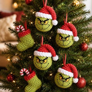 Può includere: Una collezione di ornamenti all'uncinetto fatti a mano appesi a un albero di Natale. Il set include tre teste di personaggio rotonde e verdi con cappelli da Babbo Natale rossi e bianchi e due calze all'uncinetto verdi con bastoncini.