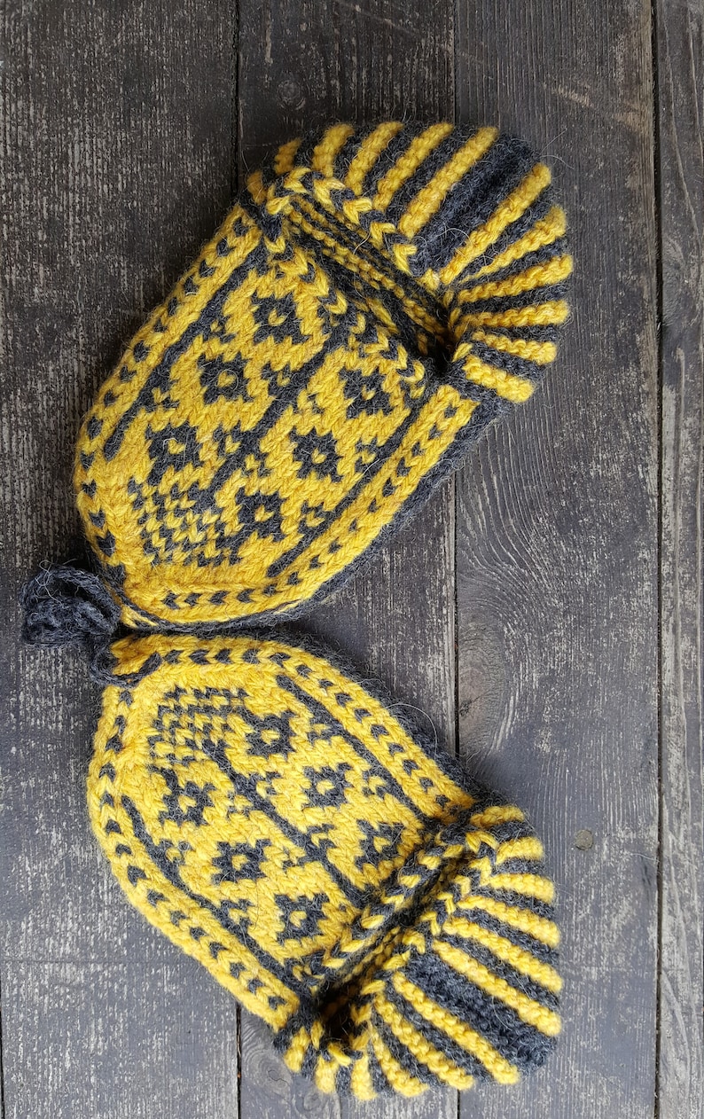 Puede incluir: Un par de zapatillas tejidas a mano con un patr&oacute;n geom&eacute;trico en amarillo vibrante y gris carb&oacute;n oscuro. Las zapatillas presentan un dise&ntilde;o de pu&ntilde;o acanalado y una construcci&oacute;n de punto texturizado con una peque&ntilde;a trabilla gris oscuro.
