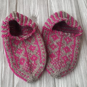 Puede incluir: Un par de zapatillas tejidas a mano con un patr&oacute;n geom&eacute;trico en magenta vibrante y marr&oacute;n claro. Las zapatillas tienen un dise&ntilde;o de punta, una abertura con borde acanalado y una construcci&oacute;n de punto texturizado en toda la superficie.