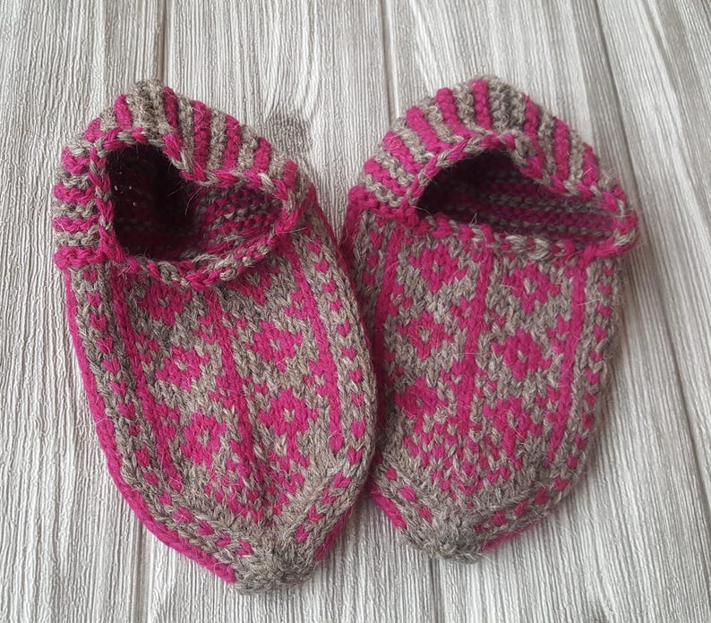 Puede incluir: Un par de zapatillas tejidas a mano con un patr&oacute;n geom&eacute;trico en magenta vibrante y marr&oacute;n claro. Las zapatillas tienen un dise&ntilde;o de punta, una abertura con borde acanalado y una construcci&oacute;n de punto texturizado en toda la superficie.