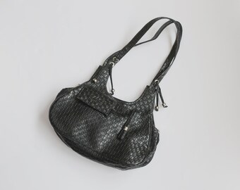 May include: A black woven leather handbag with a single strap and a small pocket on the front.