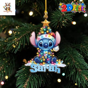 May include: A flat, hanging Christmas ornament featuring the blue character Stitch wearing a Santa hat, wrapped in colorful string lights, and topped with a gold star. The name Sarah is printed in large blue letters on a white base at the bottom.