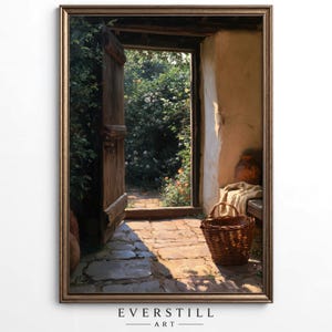 May include: A framed wall art print depicting an open wooden door leading to a sunlit garden path. The scene features a stone floor, a woven wicker basket, a draped beige cloth, and a terracotta vessel, all set against a textured wall.