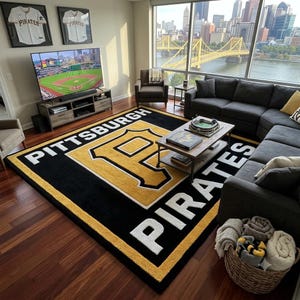 Peut inclure: Un grand tapis rectangulaire présentant le logo noir et or des Pittsburgh Pirates au centre, avec le mot Pittsburgh en lettres blanches au-dessus du logo et le mot Pirates en lettres blanches sous le logo sur un fond noir.