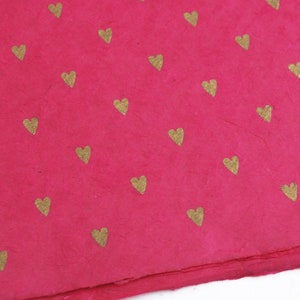 Corazones dorados sobre papel lokta de comercio justo hecho a mano en color cereza, papel de regalo rosa