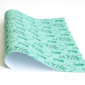 May include: A roll of turquoise blue wrapping paper with a repeating pattern of white sea turtles and green seahorses.