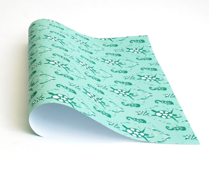 May include: A roll of turquoise blue wrapping paper with a repeating pattern of white sea turtles and green seahorses.