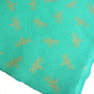 May include: Teal blue wrapping paper with a repeating pattern of gold dragonfly silhouettes.