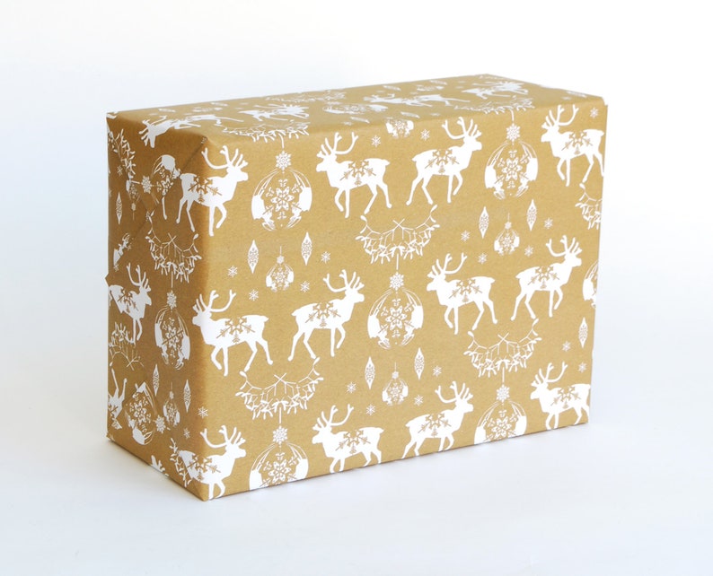 May include: Brown wrapping paper with a white reindeer pattern. The reindeer are silhouetted and have a simple design. The paper also has a white snowflake pattern.