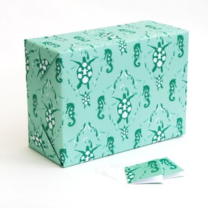 May include: A turquoise gift wrap with a repeating pattern of sea turtles and seahorses. The pattern is in a darker shade of green.