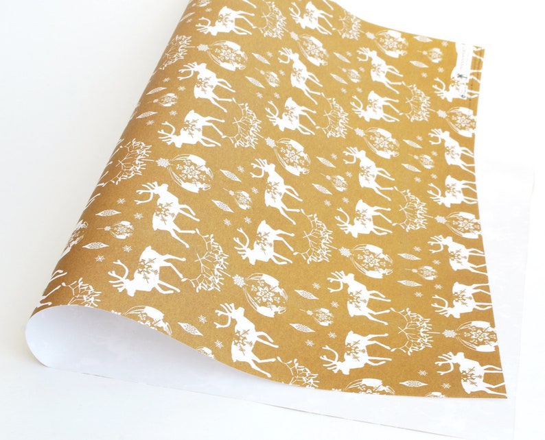 May include: Brown wrapping paper with a white reindeer pattern. The reindeer are silhouetted and have a snowflake design on their antlers.