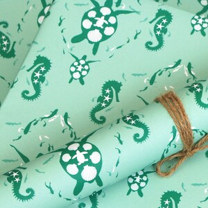 May include: Teal blue wrapping paper with a repeating pattern of seahorses and sea turtles. The seahorses are green and have white stars on them. The sea turtles are green and have white shells.