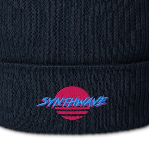 Classic organic cotton ribbed beanie. Synthwave in retro front in bright blue with hot pink shadow over a sunset in hot pink.
6 colours available.
Oxford Navy
Black
Light Avio Blue
Light Grey
Leaf Green
Mustard Yellow.
Oxford navy shown.