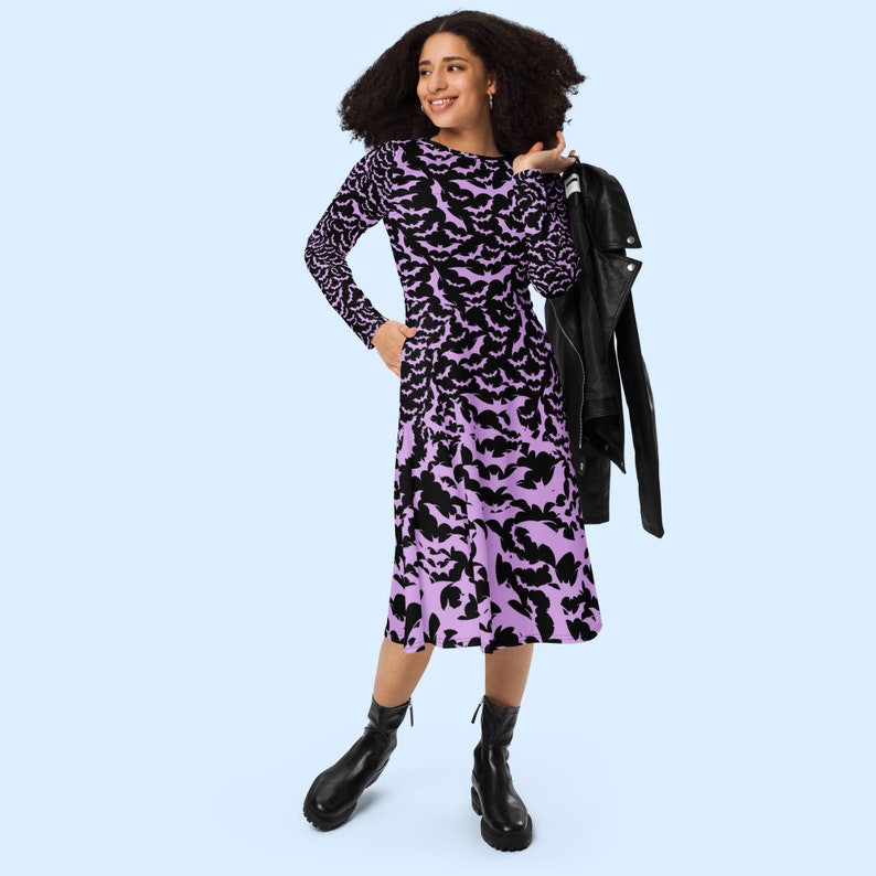 Bats dress. Long sleeves. Midi length (below the knee). Flared skirt. Pockets. Black base with bats of varying sizes in pastel purple (lilac) forming an all over pattern. The skirt has larger bats overlapping each other. With jacket and boots.