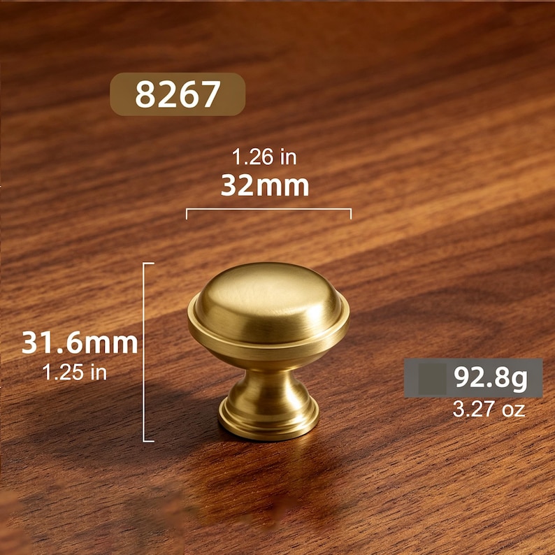 May include: A gold-toned metal cabinet knob with a smooth, rounded top and a tapered base. The knob is labeled with the number 8267 and has a diameter of 1.26 inches, a height of 1.25 inches, and a weight of 3.27 ounces as indicated in the image.