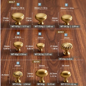 May include: A collection of nine brass-toned metal cabinet knobs in various shapes and sizes, labeled with model numbers 8067, 8093, and 8094. Each knob includes printed specifications for diameter, height, and weight in both metric and imperial units.