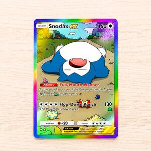 Könnte beinhalten: Eine Snorlax ex Sammelkarte mit einem regenbogenfarbenen holografischen Rand. Die Karte zeigt ein blau-weißes Snorlax, das auf einem Weg liegt, mit dem Text Snorlax ex, 160 HP, Ability Full-Mouth Manner und Flop-Down Punch 130.