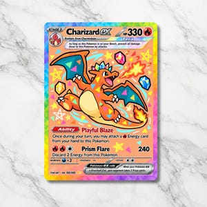 May include: A rectangular Charizard ex trading card with a rainbow holographic border. The card features an orange Charizard character with blue wings, surrounded by colourful geometric shapes, stars, and crystals against a peach background.