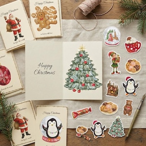 Puede incluir: Una colección de tarjetas de felicitación navideñas y pegatinas decorativas con ilustraciones en acuarela de Papá Noel, un hombre de jengibre, un árbol de Navidad, pingüinos, un elfo, un oso y dulces, con el texto Happy Christmas.
