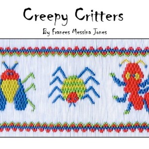 May include: A white fabric with a red, green, and blue embroidered border. The border has a repeating pattern of small hearts. The fabric features three embroidered insects: a red and yellow ladybug, a green and yellow spider, and a red ant.
