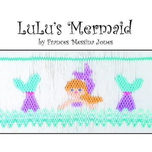 May include: A white fabric with a green, purple and orange embroidered design of a mermaid with two fish tails. The text "Lulu's Mermaid" and "by Frances Messina Jones" is embroidered on the fabric.
