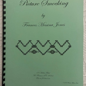 May include: A green book with the title "Picture Smocking" by Frances Messina Jones. The book has a spiral binding and a decorative design on the front cover.