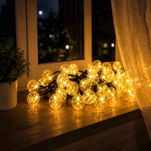 May include: A string of decorative globe lights featuring clear, textured spherical bulbs that emit a warm, golden glow. The lights are arranged in a cluster on a wooden surface, with each bulb displaying an intricate, crackled pattern.