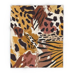 May include: A square fabric blanket featuring a multi-layered animal print pattern. The design incorporates abstract shapes in shades of mustard yellow, terracotta, cream, and dark brown, including leopard spots and tiger-like black stripes.