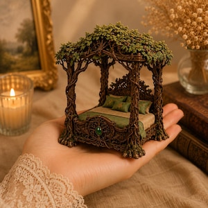 May include: A miniature four-poster bed sculpture featuring a brown, tree-like frame with intricate root details and a canopy of green leaves. The bed includes a green patterned mattress, two small green pillows, and a central green gemstone accent.