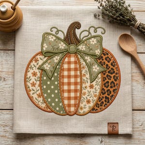 May include: A light beige linen tea towel featuring an embroidered pumpkin design. The pumpkin is composed of various fabric patterns including orange gingham, green polka dots, floral prints, and leopard print, topped with a large sage green floral bow.