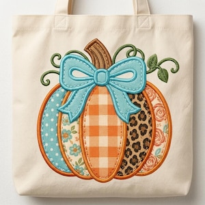 May include: A cream-colored canvas tote bag featuring a large embroidered pumpkin design. The pumpkin has segments with blue polka dots, blue floral patterns, orange gingham, leopard print, and orange roses, topped with a light blue bow.