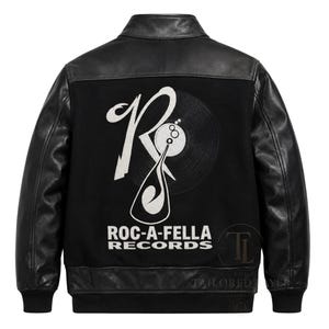 Op de afbeelding: Een zwart varsity jack met leren mouwen en een body van wolmix. Op de achterkant staat een groot wit geborduurd Roc-A-Fella Records-logo, inclusief een gestileerde letter R, een vinylplaat-afbeelding en de tekst ROC-A-FELLA RECORDS.
