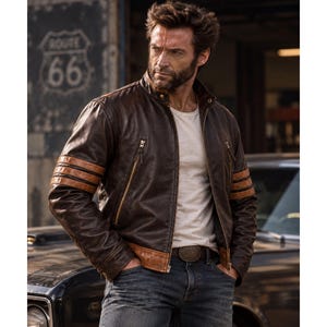 Könnte beinhalten: Eine dunkelbraune Lederjacke mit Stehkragen, goldfarbenen Reißverschlüssen und drei horizontalen hellbraunen Streifen an jedem Ärmel. Die Jacke wird über einem schlichten weißen T-Shirt und einer blauen Jeans mit dunklem Ledergürtel getragen.