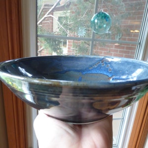 May include: A large, blue and brown ceramic bowl with a glossy finish. The bowl has a wide rim and a deep, rounded shape.
