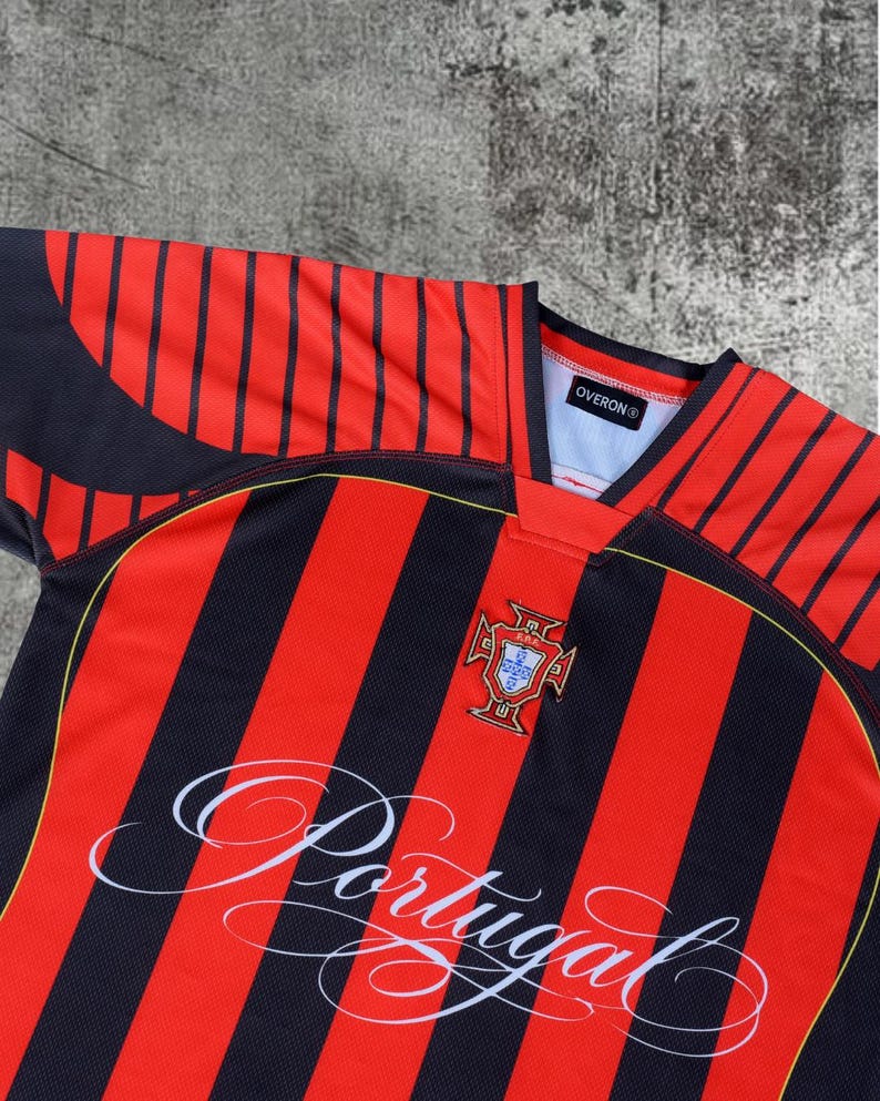 May include: A short-sleeved sports jersey featuring vertical black and red stripes. The chest displays the Portugal national team crest and the word Portugal in white cursive script. The collar is black and red with an Overon brand label inside.
